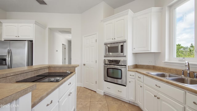 kitchen with light tile patterned floors, visible vents, appliances with stainless steel finishes, white cabinets, and a sink