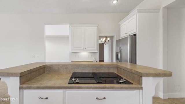 kitchen with white cabinetry, stainless steel fridge, and black electric cooktop