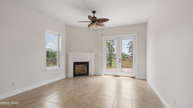 unfurnished living room featuring french doors, a fireplace, plenty of natural light, and baseboards