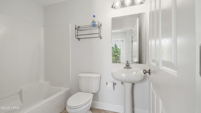 bathroom featuring toilet, baseboards, and shower / washtub combination