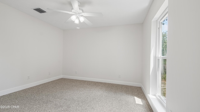 empty room with carpet floors, baseboards, visible vents, and a ceiling fan