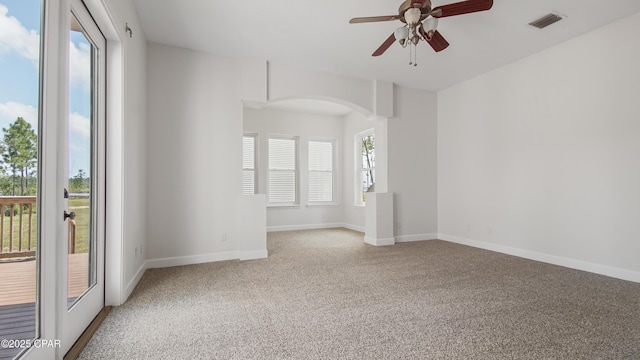 spare room featuring arched walkways, visible vents, light carpet, ceiling fan, and baseboards