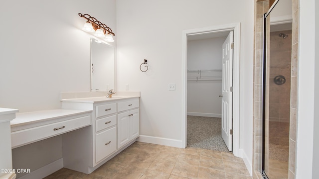 bathroom featuring a stall shower, baseboards, tile patterned floors, a spacious closet, and vanity