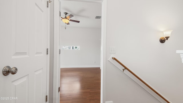 corridor featuring baseboards, visible vents, wood finished floors, and an upstairs landing