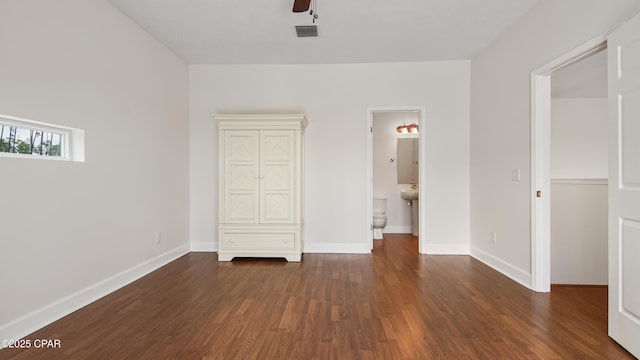 unfurnished bedroom featuring baseboards, visible vents, wood finished floors, and ensuite bathroom