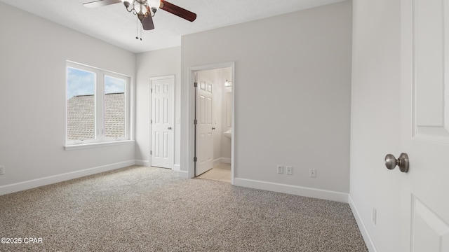 unfurnished bedroom featuring light carpet, connected bathroom, baseboards, and ceiling fan