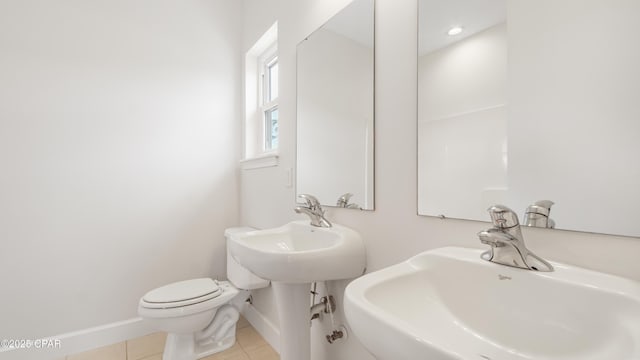 half bathroom featuring tile patterned flooring, baseboards, a sink, and toilet