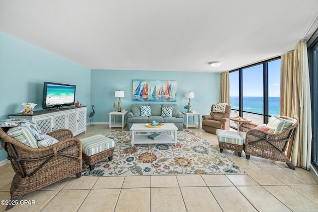 tiled living room featuring a wall of windows, baseboards, and a water view