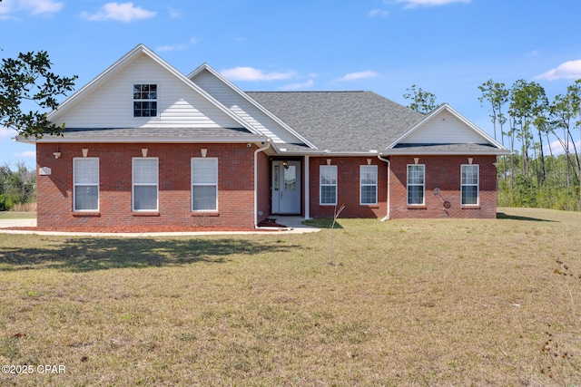 view of front of home featuring a shingled roof, a front yard, and brick siding