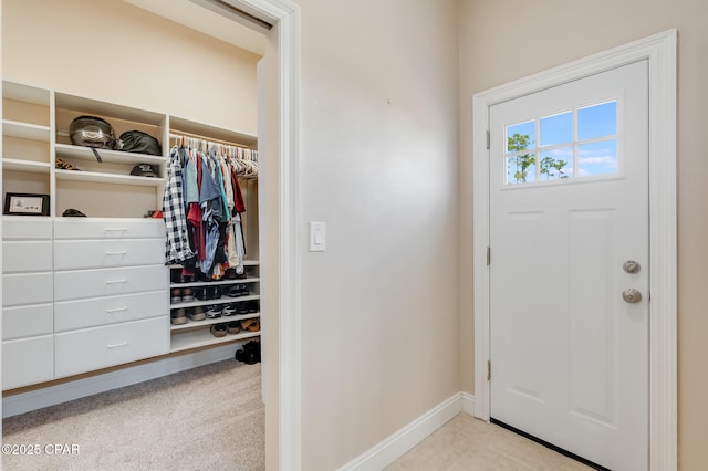 entryway with light tile patterned floors, light colored carpet, and baseboards