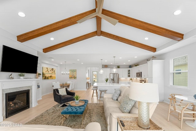 living area with light wood-type flooring, a glass covered fireplace, vaulted ceiling with beams, and recessed lighting