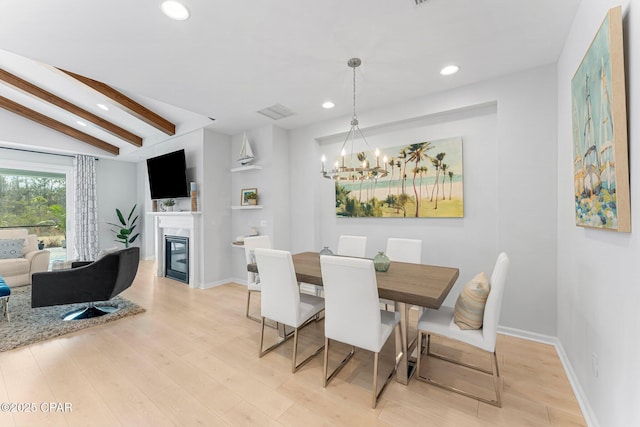 dining area with lofted ceiling with beams, light wood finished floors, a glass covered fireplace, and recessed lighting