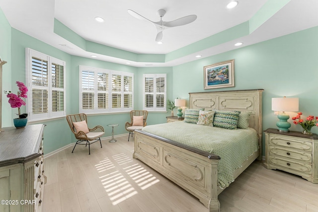 bedroom with light wood-style floors, baseboards, a tray ceiling, and recessed lighting