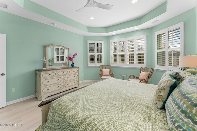 bedroom with a tray ceiling, recessed lighting, baseboards, and wood finished floors