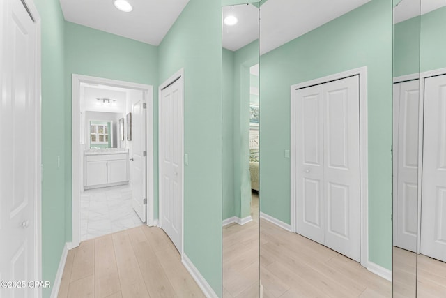 hall featuring light wood-style floors, baseboards, and recessed lighting