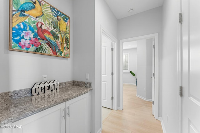 hallway with light wood-type flooring and baseboards