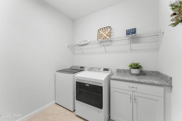 clothes washing area featuring cabinet space, washing machine and dryer, baseboards, and light tile patterned flooring