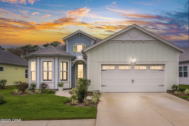 view of front of property featuring a shingled roof, an attached garage, board and batten siding, a front yard, and driveway