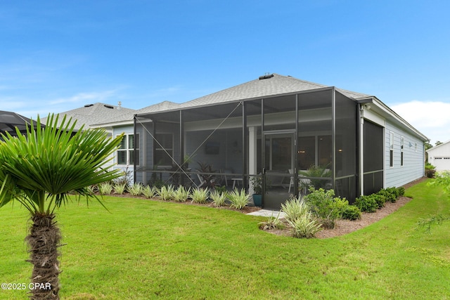 rear view of property featuring a yard, a shingled roof, and a lanai