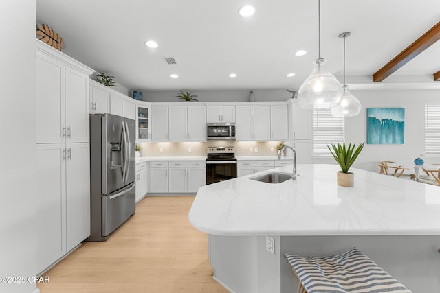 kitchen featuring appliances with stainless steel finishes, white cabinetry, a sink, and visible vents