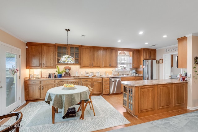 kitchen with decorative backsplash, light wood-style flooring, glass insert cabinets, appliances with stainless steel finishes, and crown molding