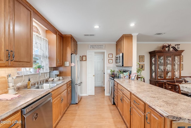 kitchen with ornamental molding, appliances with stainless steel finishes, a sink, and visible vents