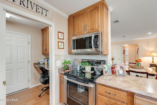 kitchen featuring stainless steel appliances, visible vents, ornamental molding, built in study area, and decorative backsplash