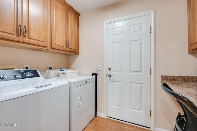 washroom with light wood-style floors, cabinet space, and washer and clothes dryer