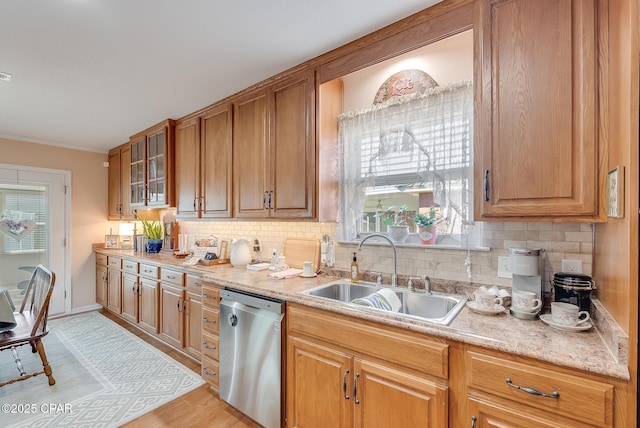 kitchen with decorative backsplash, glass insert cabinets, ornamental molding, stainless steel dishwasher, and a sink