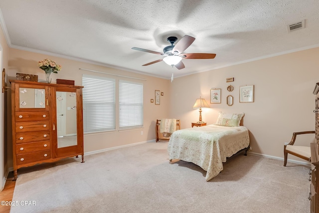 bedroom featuring ornamental molding, visible vents, a textured ceiling, and baseboards