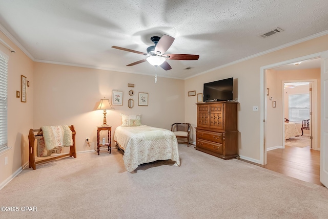 carpeted bedroom featuring ornamental molding, visible vents, a textured ceiling, and baseboards