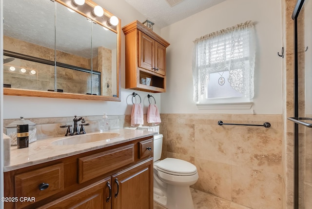 bathroom featuring a shower with shower door, a textured ceiling, toilet, and vanity