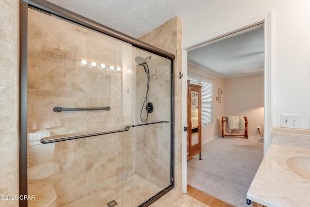 full bath featuring baseboards, vanity, crown molding, a textured ceiling, and a shower stall