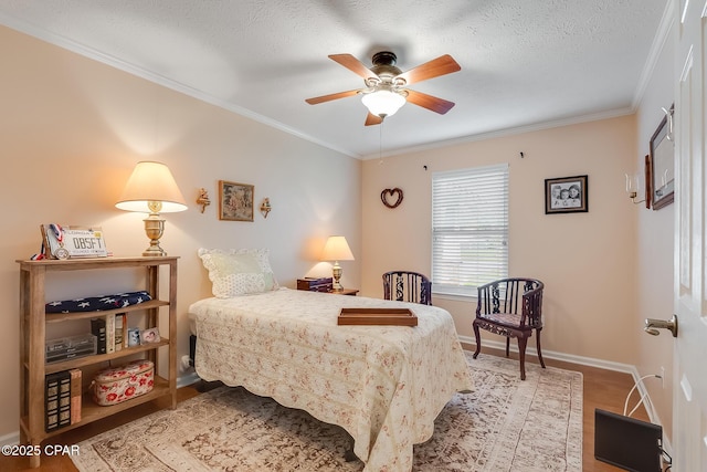 bedroom featuring a textured ceiling, ornamental molding, a ceiling fan, and baseboards