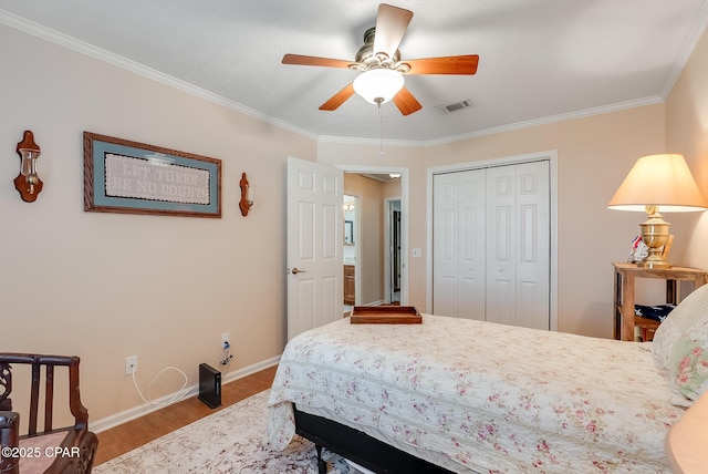 bedroom featuring crown molding, a closet, visible vents, wood finished floors, and baseboards