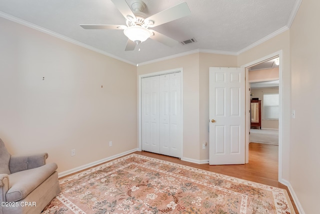 living area featuring baseboards, visible vents, ceiling fan, wood finished floors, and crown molding