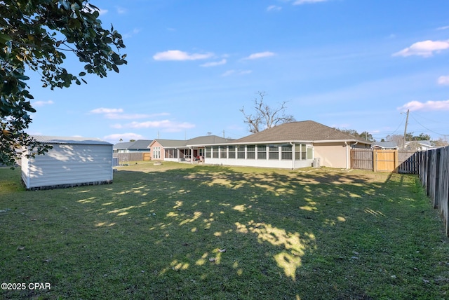 back of house with a yard, a storage shed, a sunroom, a fenced backyard, and an outdoor structure