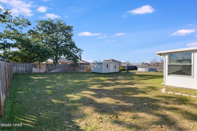 view of yard with an outbuilding, a fenced backyard, and a storage unit