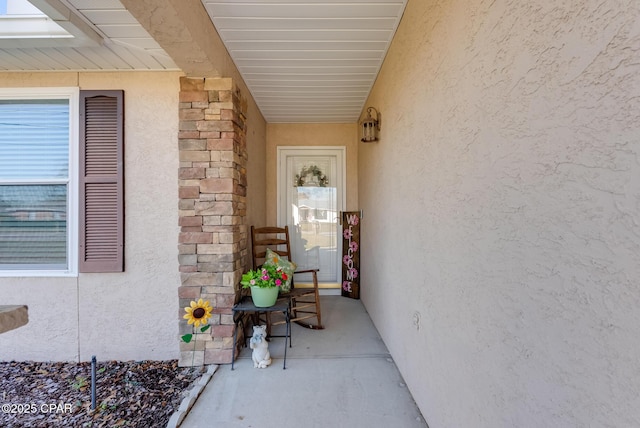 view of exterior entry with stone siding and stucco siding