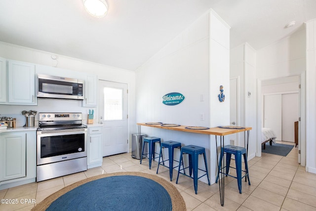 5801 Pinetree Avenue A, B, C & D, Panama City, FL 32408 - kitchen with stainless steel appliances, a kitchen bar, light tile patterned floors, and high vaulted ceiling
