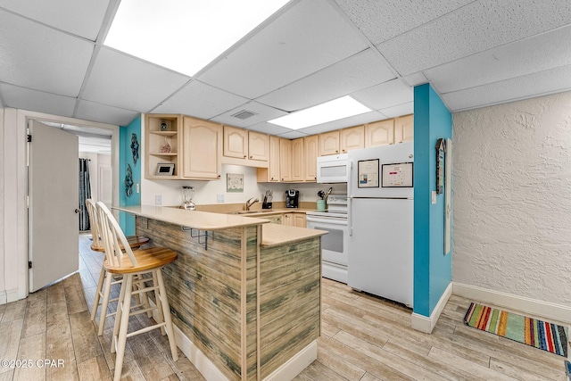 kitchen with visible vents, light brown cabinetry, light wood-type flooring, white appliances, and a drop ceiling