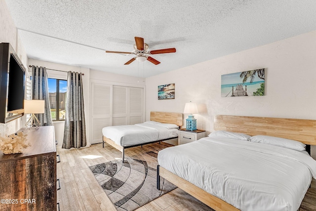 bedroom with a closet, a textured ceiling, ceiling fan, and wood finished floors