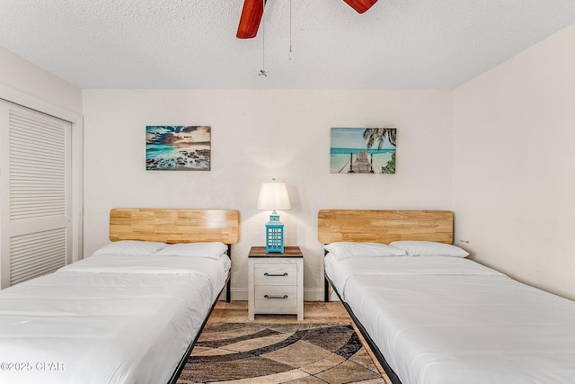 bedroom with a ceiling fan, a closet, a textured ceiling, and baseboards