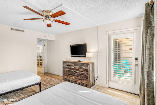 bedroom with visible vents, ceiling fan, a textured ceiling, and wood finished floors