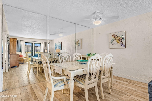 dining area with a textured wall, light wood-style flooring, a textured ceiling, and ceiling fan