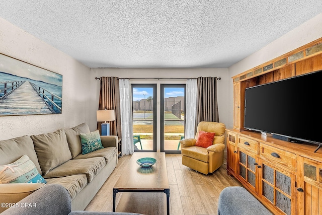 living area with a textured wall, a textured ceiling, and hardwood / wood-style flooring