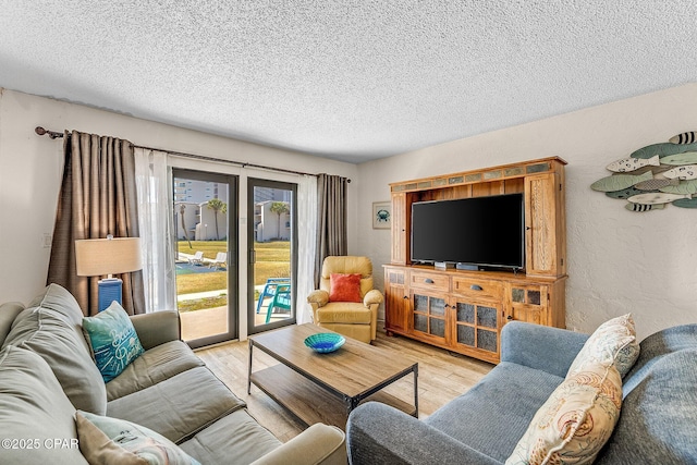 living area featuring light wood-style floors, a textured wall, and a textured ceiling