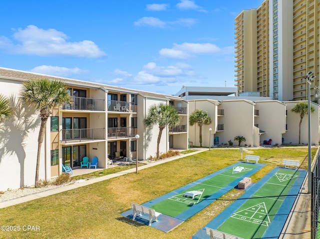 view of home's community featuring shuffleboard and a yard