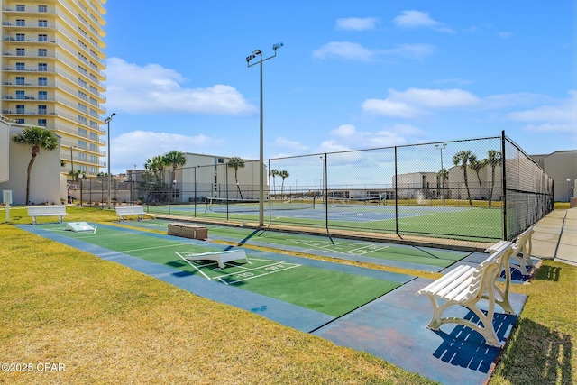 view of home's community featuring shuffleboard, a lawn, fence, and a tennis court