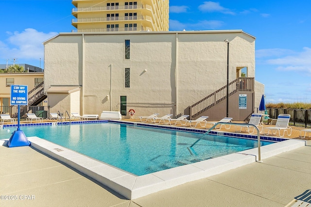 pool with a patio, stairway, and fence